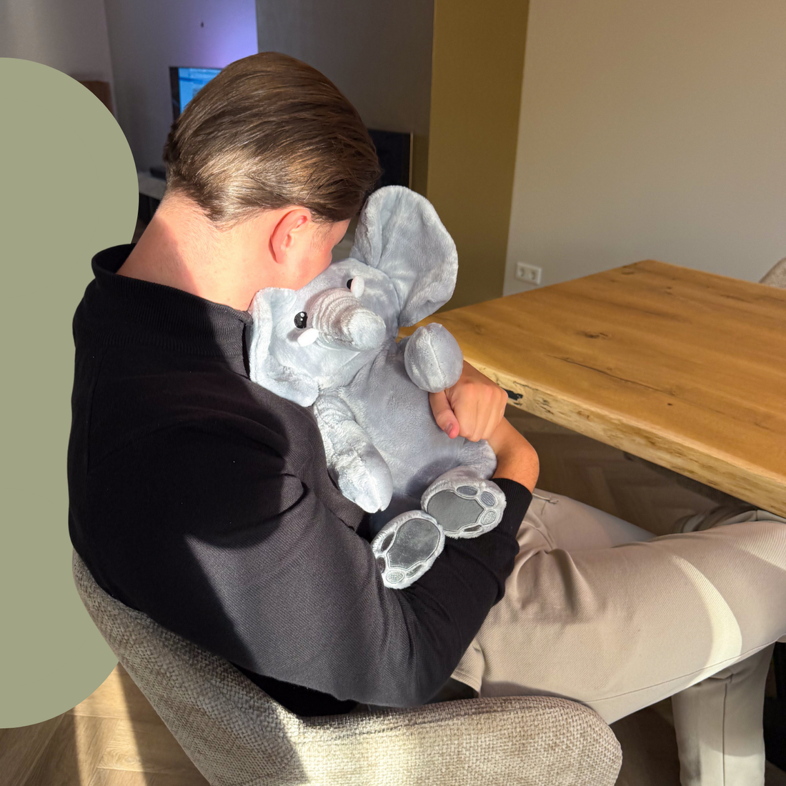 Man ontspant met verzwaarde Hugsback olifant knuffel, rust en geborgenheid aan tafel