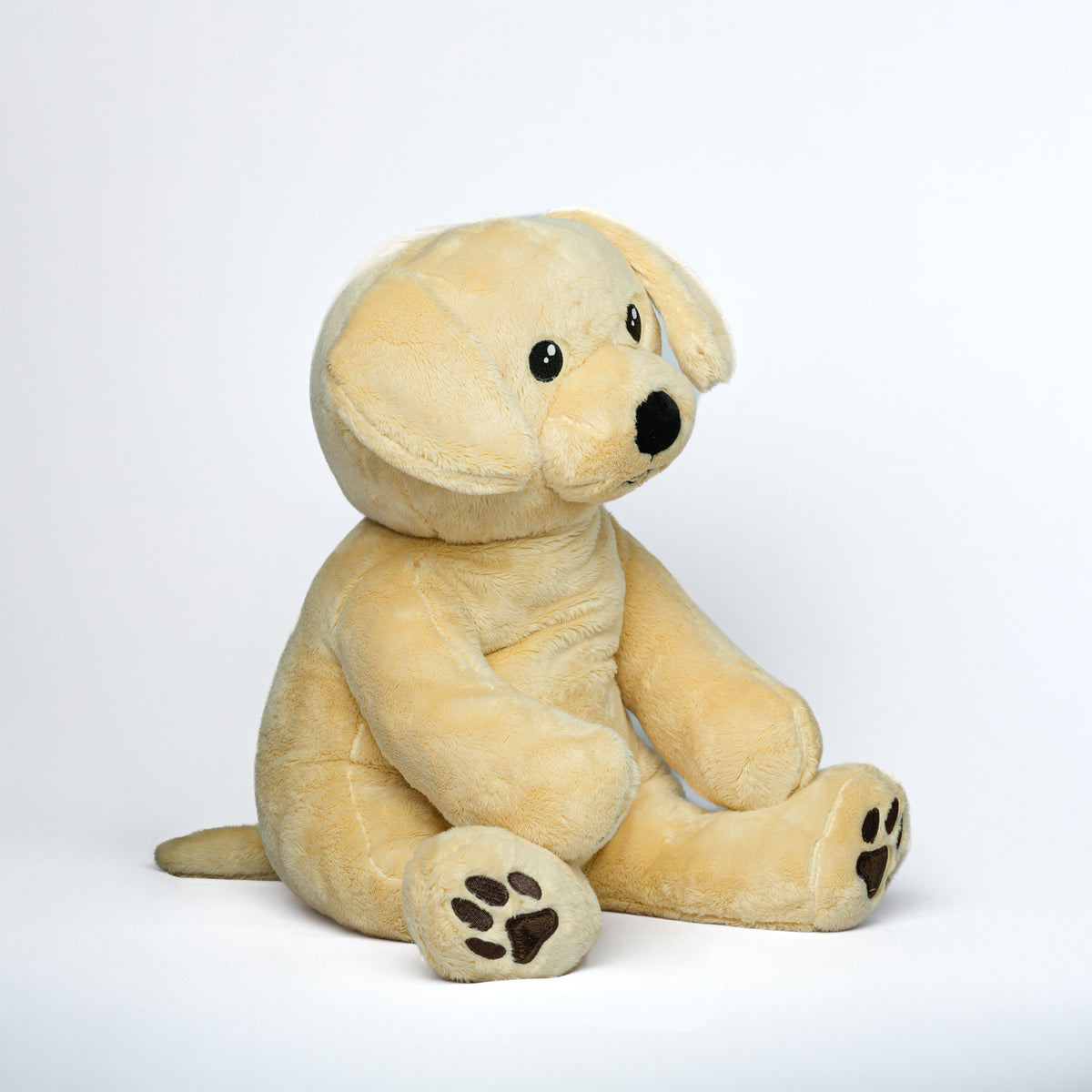 Beige Hugsback weighted plush dog, side view on a white background