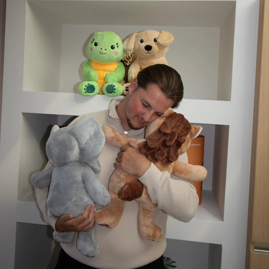 Ung mand krammer Hugsback-elefanten og Hugsback-hesten foran et skab med gaverør