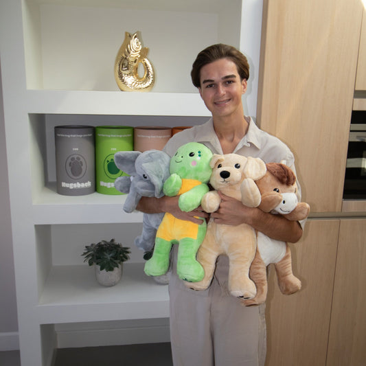 Smiling young man with all four Hugsback weighted plush toys in his arms