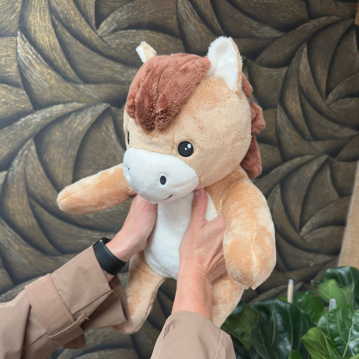 Mains soulevant la peluche lestée cheval Hugsback marron