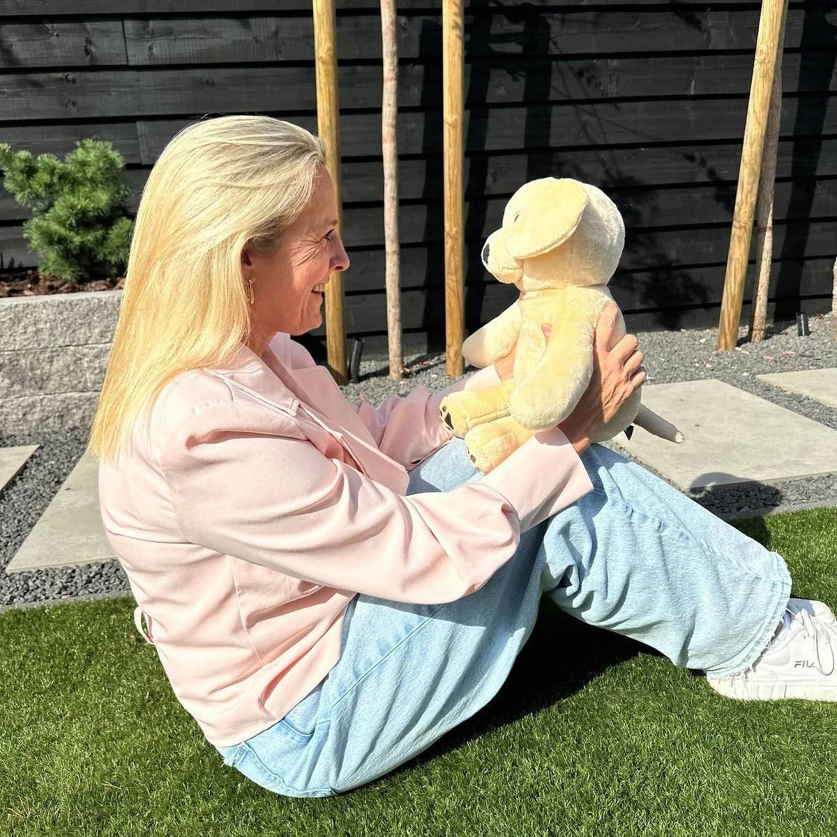 Woman with the beige Hugsback weighted plush dog in the garden