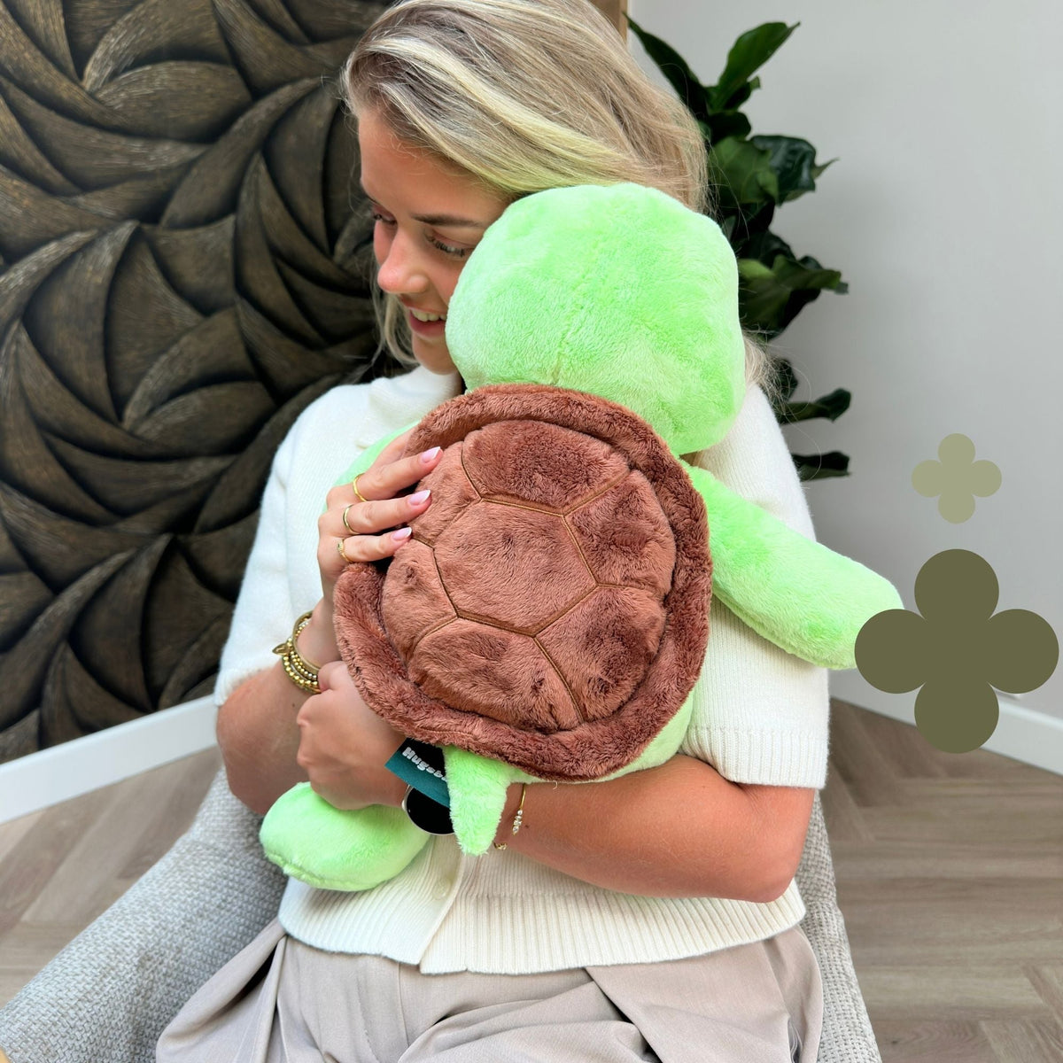 Vrouw knuffelt de groene Hugsback verzwaringsknuffel schildpad met het bruine schild in beeld