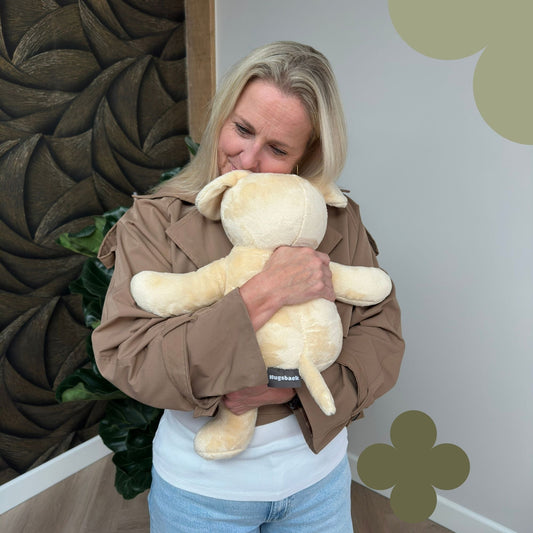 Vrouw knuffelt de beige Hugsback verzwaringsknuffel hond