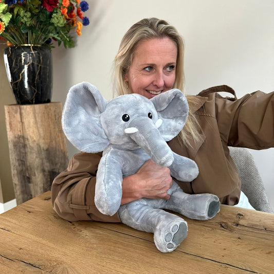 Femme avec la peluche lestée éléphant Hugsback grise sur les genoux à table