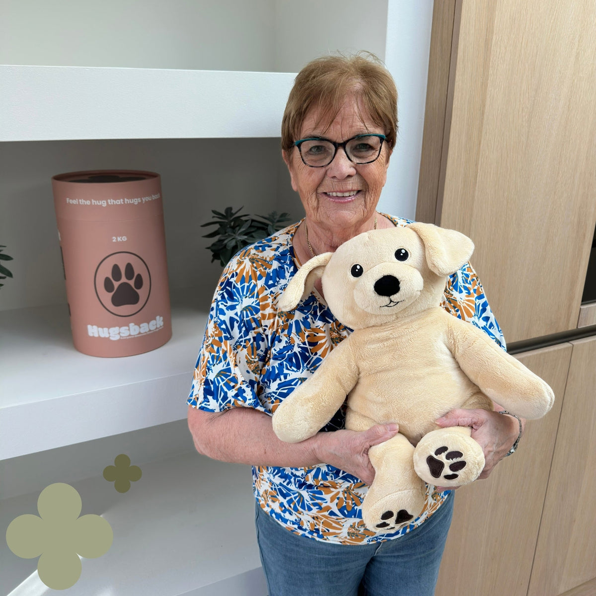 Oudere vrouw met de beige Hugsback Hond bij de roze cadeaukoker