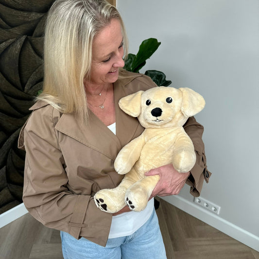 Lachende vrouw houdt de beige Hugsback verzwaringsknuffel hond vast