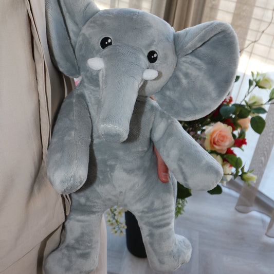 Handen houden de grijze Hugsback verzwaringsknuffel olifant vast voor een boeket bloemen