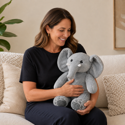 Glimlachende vrouw op de bank met de grijze verzwaringsknuffel olifant op schoot (Verified reviewer)