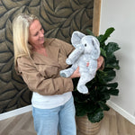 Frau, die das graue Gewichtskuscheltier Elefant vor sich hält