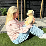Kvinde, der sidder i græsset udendørs med den beige tyngdebamse hund
