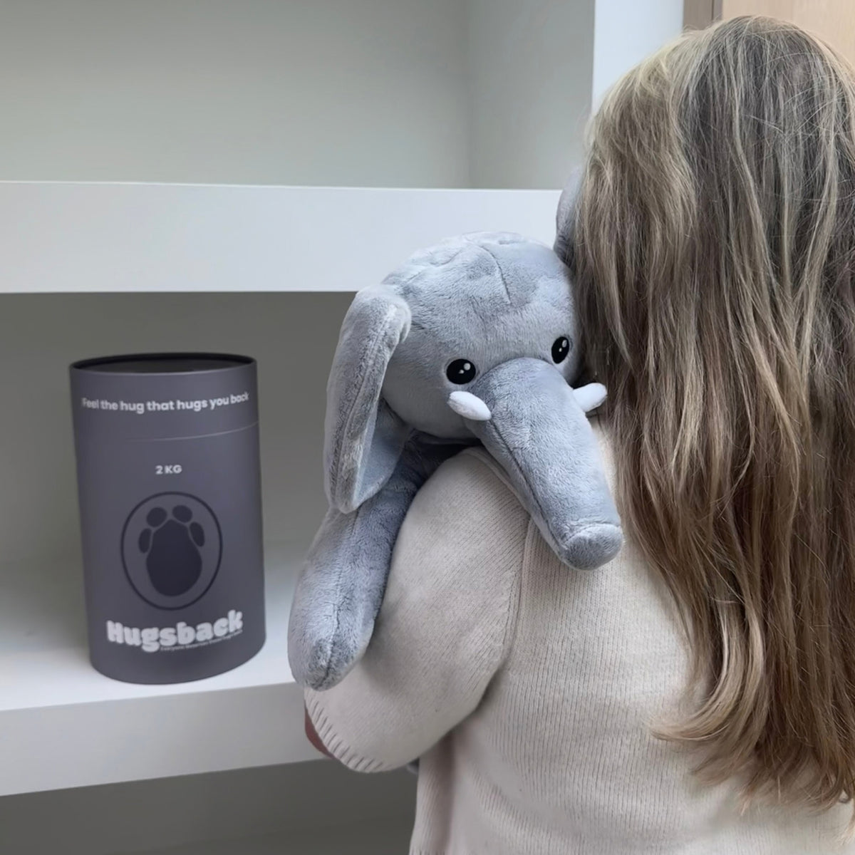 Kvinde med den grå tyngdebamse elefant over skulderen ved det grå gaverør