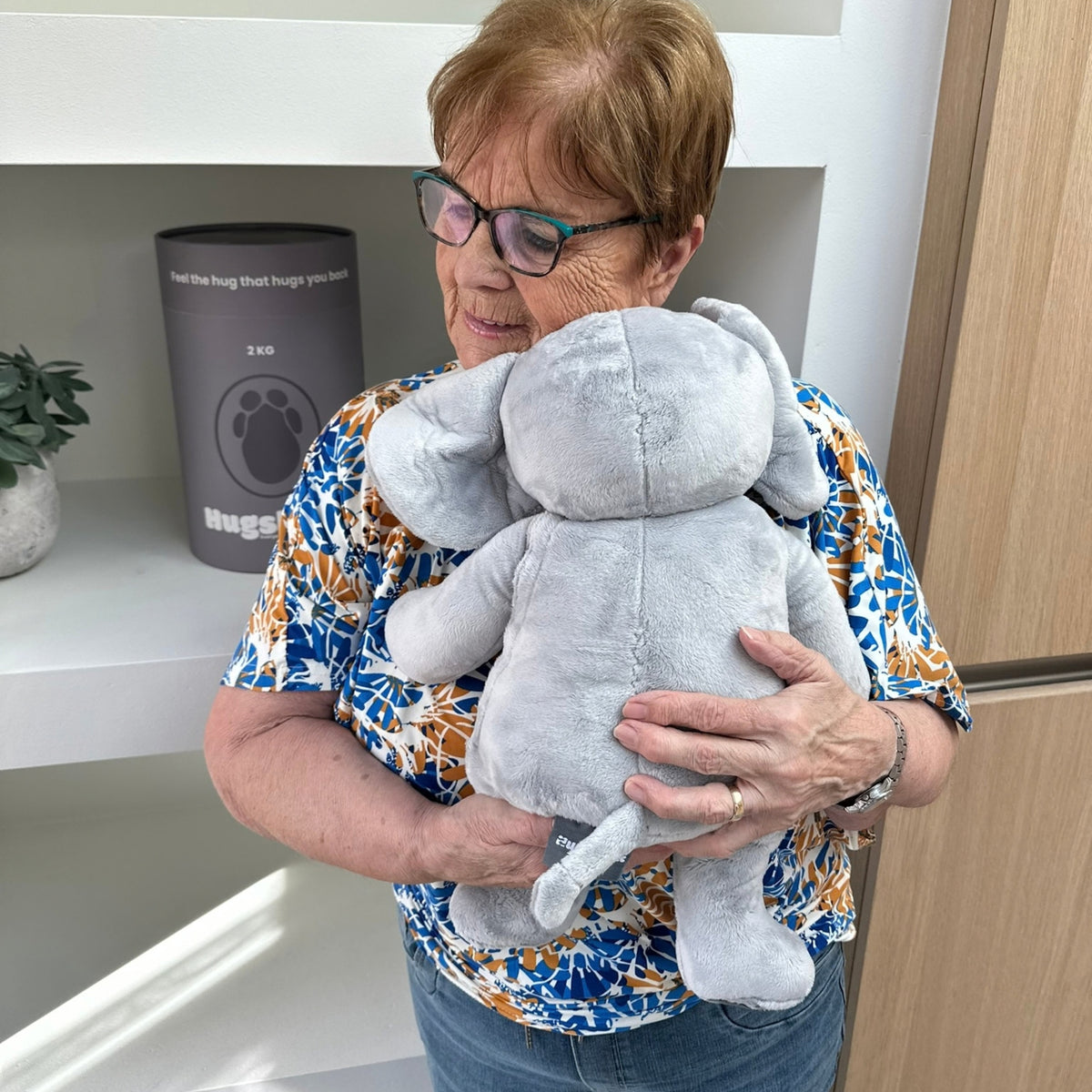 Ældre kvinde med den grå tyngdebamse elefant ved Hugsbacks grå gaverør