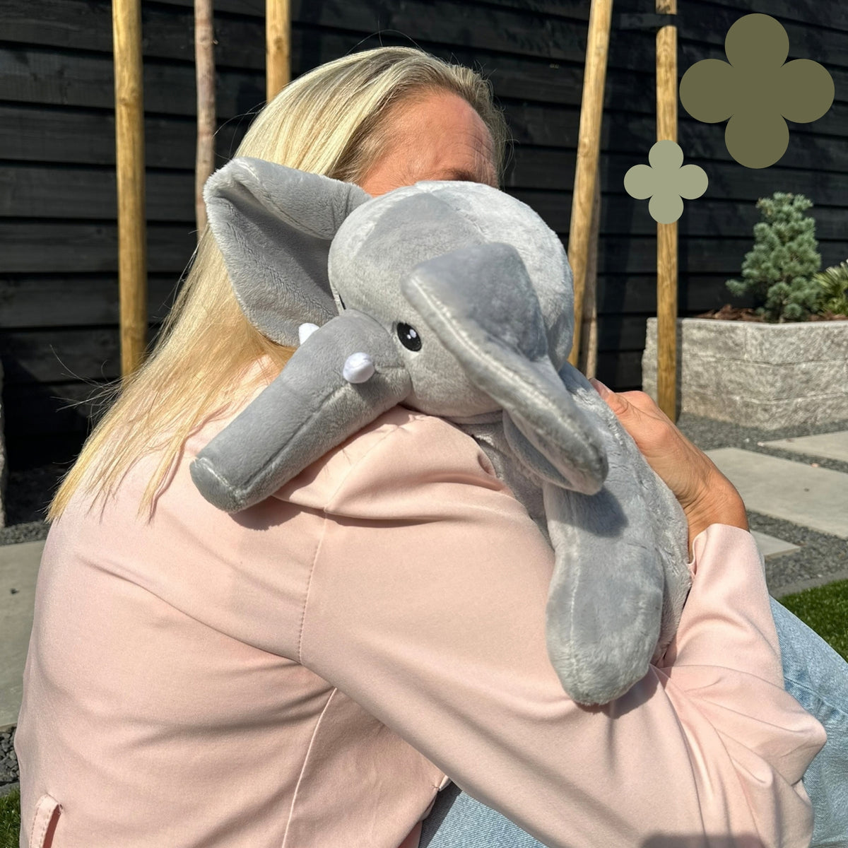 Femme qui câline la peluche lestée éléphant grise sur son épaule à l'extérieur