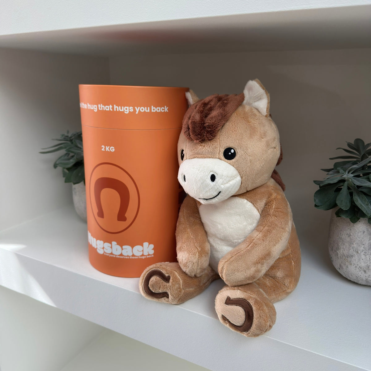 Ældre kvinde, der krammer den brune tyngdebamse hest ved Hugsbacks orange gaverør