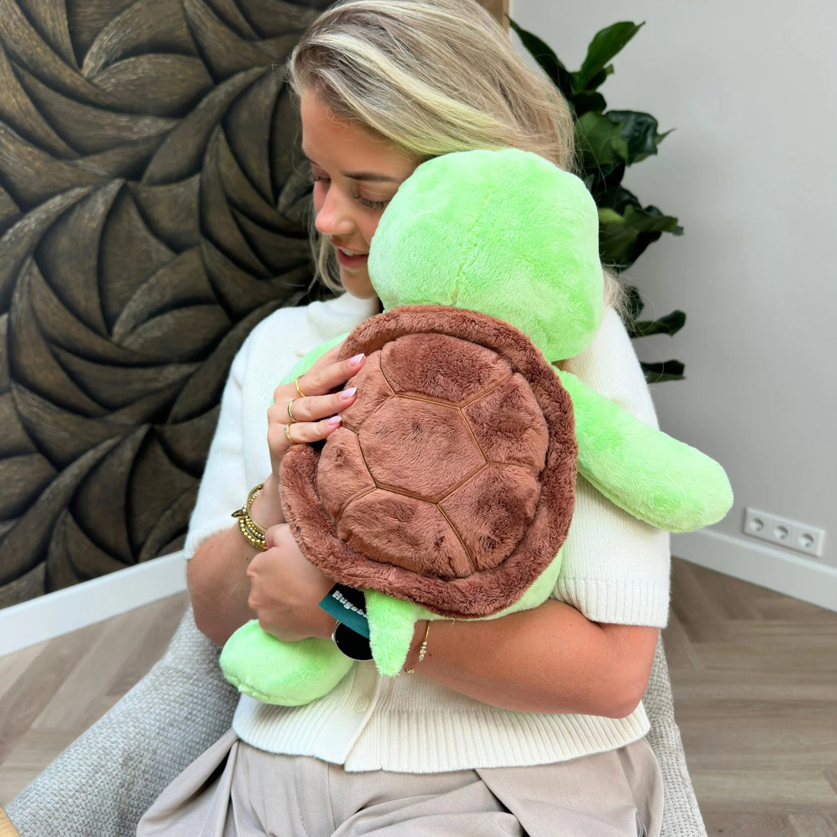 Frau, die das grüne Gewichtskuscheltier Schildkröte fest knuddelt