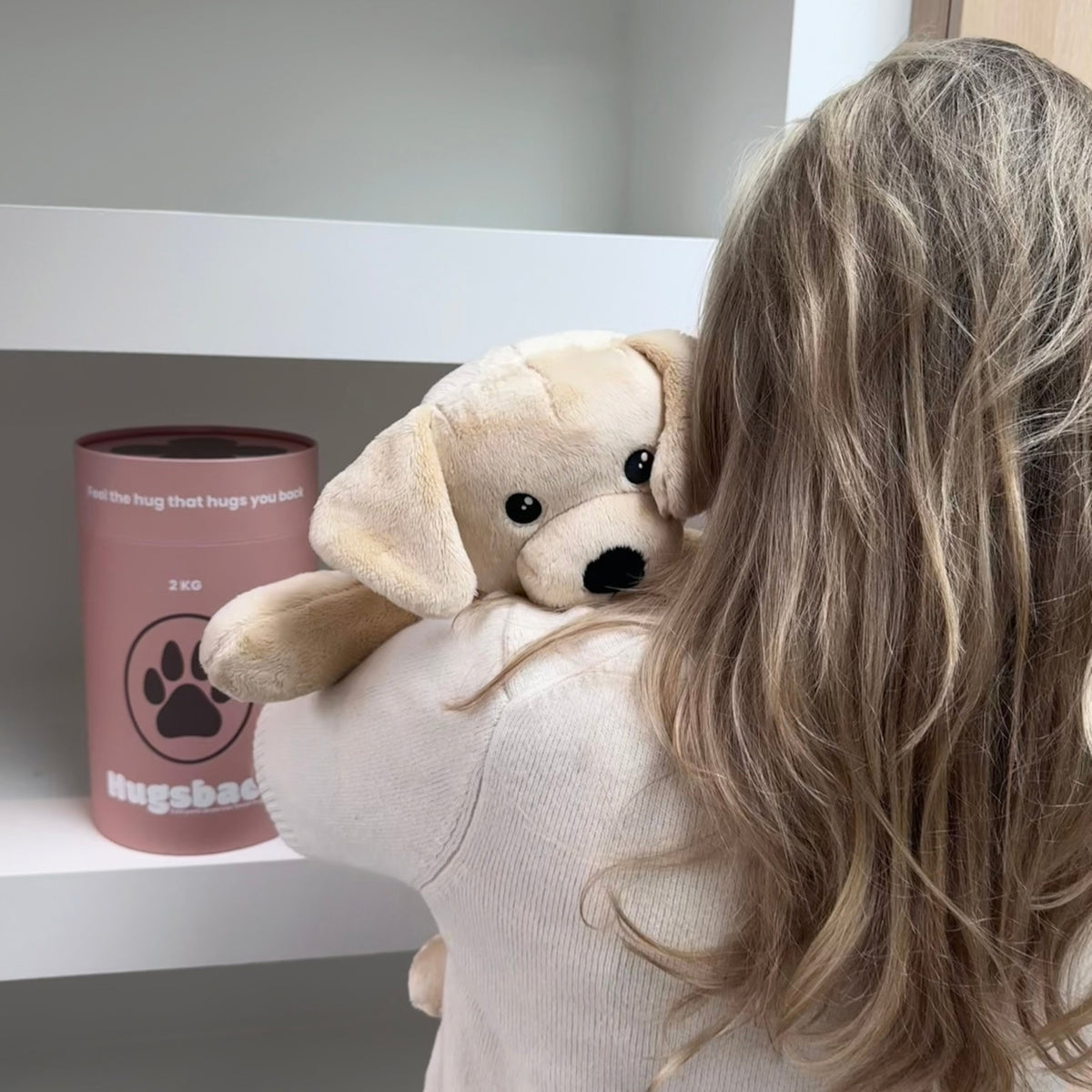 Ung kvinde med den beige tyngdebamse hund over skulderen ved det lyserøde gaverør