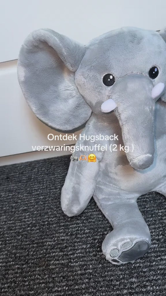 Video waarin de Hugsback verzwaringsknuffel olifant van 2 kg wordt getoond op een grijs vloerkleed