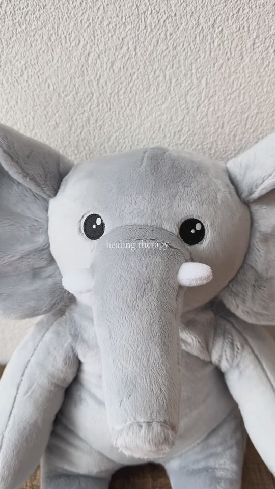 Video van de grijze verzwaringsknuffel olifant van dichtbij voor een witte muur